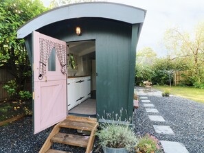 A small, enclosed structure with a pink door and a wooden staircase leading inside. - Hazel Nook (Narberth)