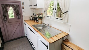 Eine kleine Küche mit einer Holzausziehtafel, einem Spülbecken und weißen Schränken.