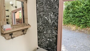 Ein Badezimmer mit einem Holzanbau, einem Spiegel und einer Tafelwand mit verschiedenen Schriftzügen und Zeichnungen.