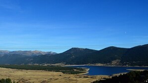 A panoramic view of a mountainous landscape with a lake and a clear sky.