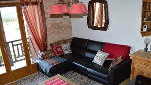 A living room with a black leather sofa, patterned rug, wooden coffee table, and a wooden side table with a lamp.