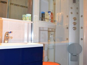 Ein Badezimmer mit einem weißen Waschbecken, einem blauen Schrank und einer Duschkabine aus Glas.