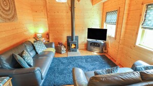 A cozy living room with a fireplace, leather sofas, a flat-screen TV, and a blue rug.