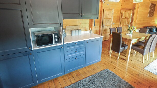 A compact kitchen with a built-in microwave, a small countertop, and a dining area with a table and chairs.
