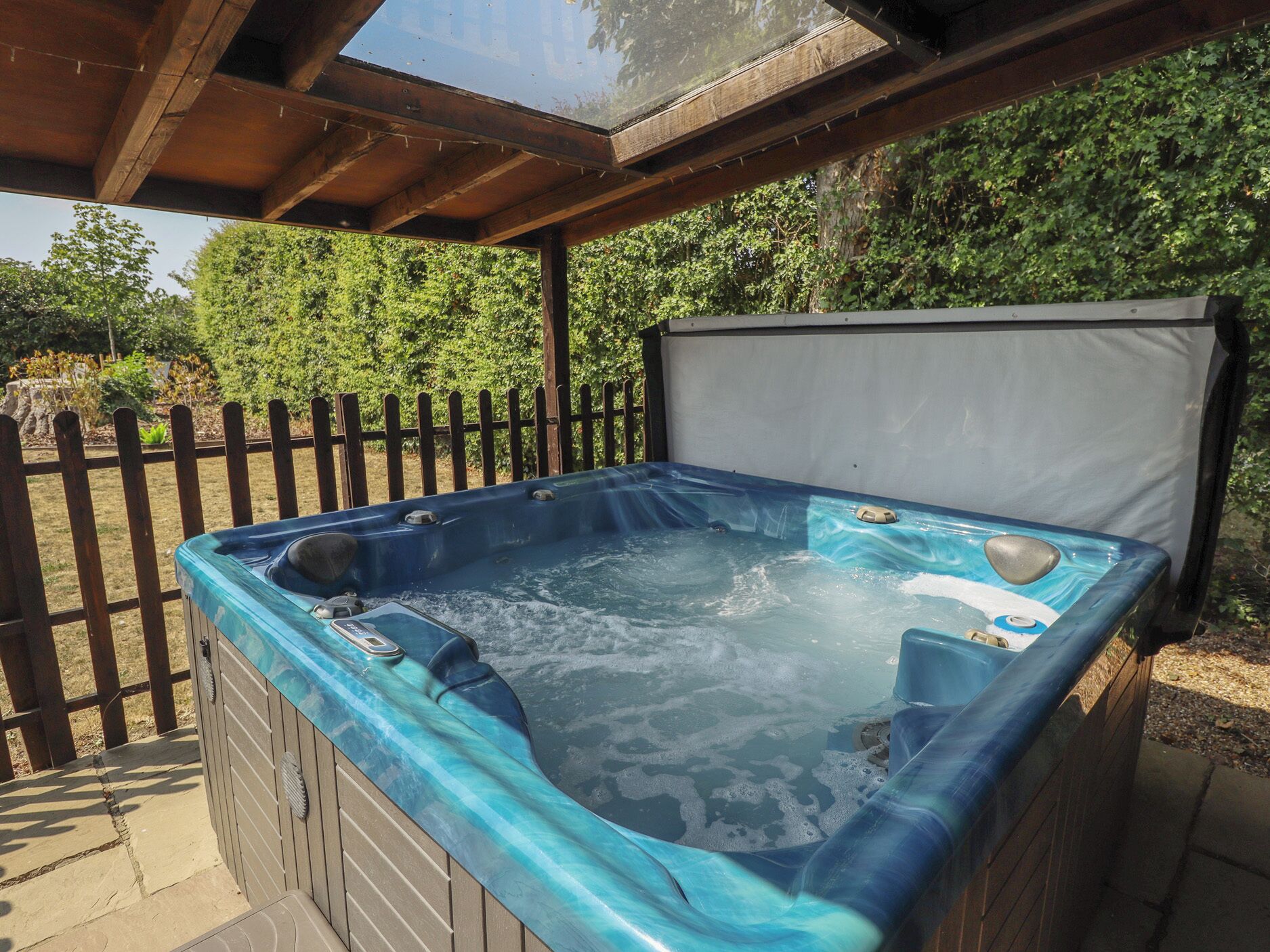 Uma banheira de hidromassagem com um deck de madeira e um cercado de madeira ao fundo.