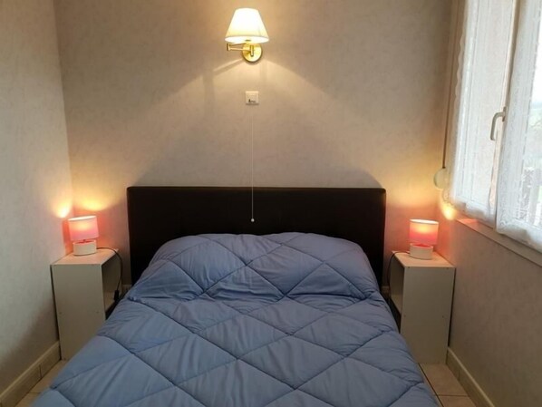 Ein Bett mit blauer Bettdecke, zwei Nachttischlampen und einer Wandleuchte.