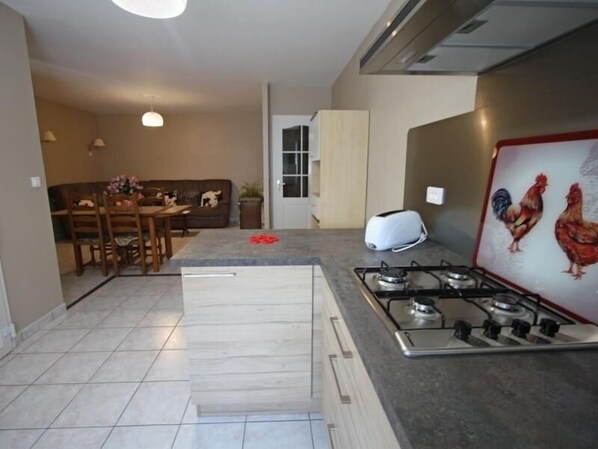 Una cocina moderna con estufa a gas, tostadora y comedor con mesa y sillas.