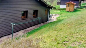 A rustic cabin with a sloped roof, a small porch, and a fenced yard. - Chalet en Forêt Hautes-Vosges avec Terrasse, Proche Gérardmer, 2 Chambres, WiFi, Équipements Complets (Rochesson)