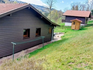 A rustic cabin with a sloped roof, a small porch, and a fenced yard.