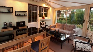 A conservatory with a dining area, a sofa, and a coffee station. - Magnificent Retreat in Vosges: Sauna, Hot Tub, Park, and More! (Colroy-la-Grande)