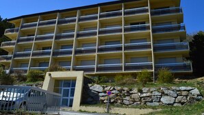 A multi-story building with balconies, a stone wall, and a gated entrance. - T2 Apartment at the foot of the slopes with parking (Les Angles)