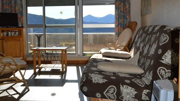A living room with a sofa, a chair, a small table, and a TV. - T2 Apartment at the foot of the slopes with parking (Les Angles)