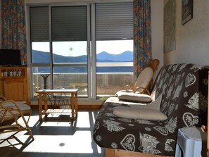 Ein Wohnzimmer mit einer Couch, einem Sessel, einem kleinen Tisch und einem Fernseher.