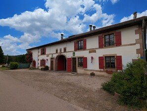 A traditional building with a large arched entrance, red shutters, and a sign indicating a restaurant.