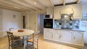 A kitchen with white cabinets, a microwave, an oven, and a herringbone-patterned backsplash. - Spacious Rustic Cottage with Terrace, Close to Gérardmer – Ideal for Families (Granges-Aumontzey-Aumontzey)