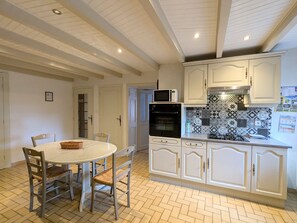 A kitchen with white cabinets, a microwave, an oven, and a herringbone-patterned backsplash.