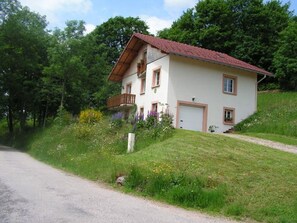 A two-story house with a sloped roof, a balcony, and a garage.