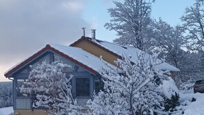 Et hus med garage, omgivet af sneklædte træer og en klar himmel.
