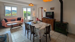 En hyggelig stue med sofa, spisebord, stole, fjernsyn og pejs.