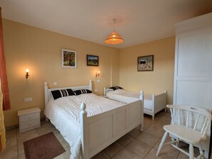 A bedroom with two single beds, a nightstand, a chair, and a hanging light fixture.