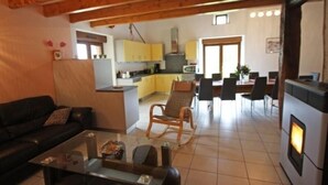 Un salon confortable avec un canapé et une table basse, un coin repas avec des chaises et une table, et une cuisine avec des meubles jaunes et une cuisinière.