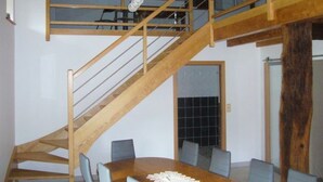 Un espace repas avec un escalier en bois menant à un niveau supérieur.