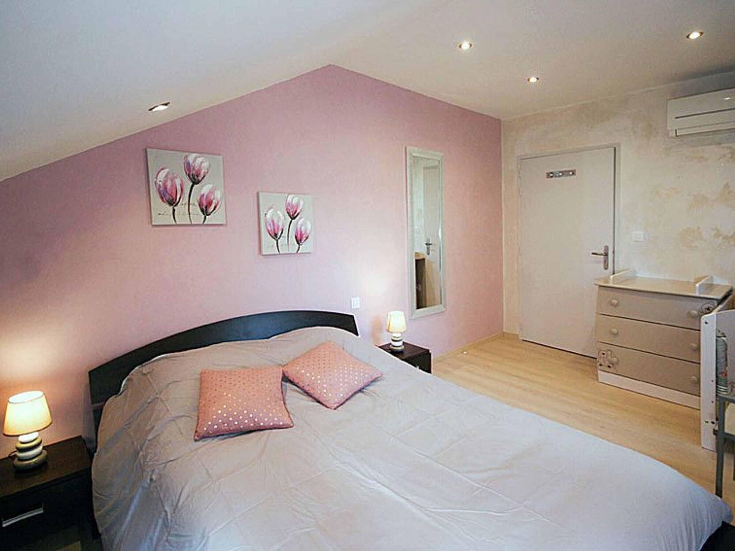 Quarto com cama, mesa de cabeceira, cômoda e espelho.