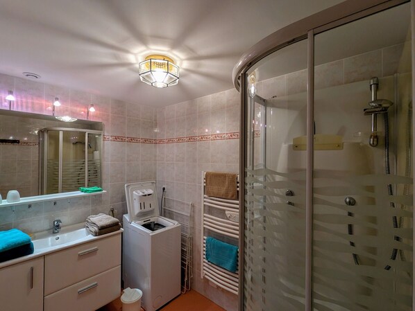 Un baño moderno con ducha envuelta en vidrio, un lavabo con espejo y un perchero para toallas.