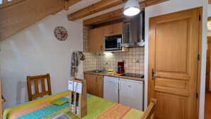 A compact kitchen with wooden cabinets, a microwave, a coffee maker, and a dishwasher.