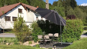 A house with a patio area featuring outdoor furniture and a large black umbrella.