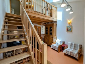 Una escalera de madera de varios niveles que conduce a un dormitorio tipo loft con una cama y un escritorio.