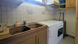 Eine Küche mit Holzausstattung, einem Doppelwaschbecken, einem eingebauten Backofen und einem Fenster über dem Waschbecken.