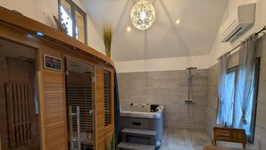 A modern bathroom with a wooden sauna, a shower, and a bench. - Chalet spacieux dans les Hautes Vosges avec sauna, spa, terrain privé et accès facile aux commodités (Fresse-sur-Moselle)