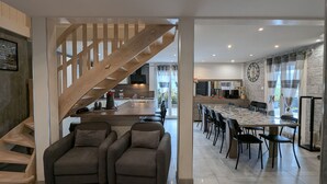A modern interior with a staircase, a dining area, and a kitchen. - Chalet spacieux dans les Hautes Vosges avec sauna, spa, terrain privé et accès facile aux commodités (Fresse-sur-Moselle)