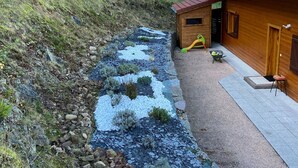 A wooden cabin with a gravel path leading to a small wooden play area. - Chalet confortable avec sauna privé, grande terrasse et accès piscine - Montagne tranquille (Ferdrupt)