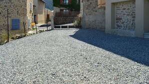 A gravel road leading to a building with stone walls and wooden balconies. - Renovated 4-bedroom village house with lake view (Les Angles)