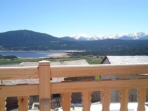 Ein Holzbalkon mit Blick auf einen See, Berge und einen klaren Himmel.