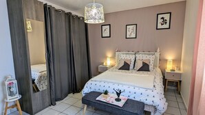 A bedroom with a bed, bedside tables, a bench, a mirror, curtains, and wall art. - Cozy Retreat for 4 with South-Facing Balcony, Garage, and Easy Access to Nature and Local Attractions (Gérardmer)