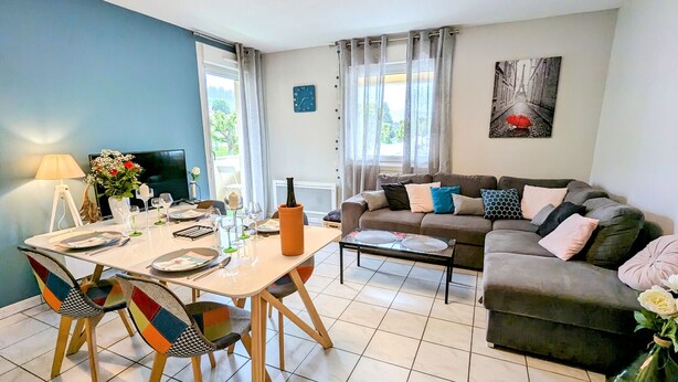A modern living room with a dining area, a sofa set, and a television. - Cozy Retreat for 4 with South-Facing Balcony, Garage, and Easy Access to Nature and Local Attractions (Gérardmer)