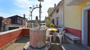 A courtyard with a decorative metal rooster sculpture, a round table with chairs, and a vase of flowers. - House 2063/32559 (Istria - Poreč), 6000m from the beach (Poreč)