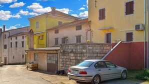 A street with yellow and white buildings, a parked car, and a clear blue sky with clouds. - House 2063/32559 (Istria - Poreč), 6000m from the beach (Poreč)