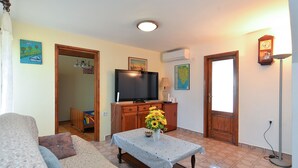 A living room with a television, a coffee table with a vase, and a sofa. - House 2063/32559 (Istria - Poreč), 6000m from the beach (Poreč)