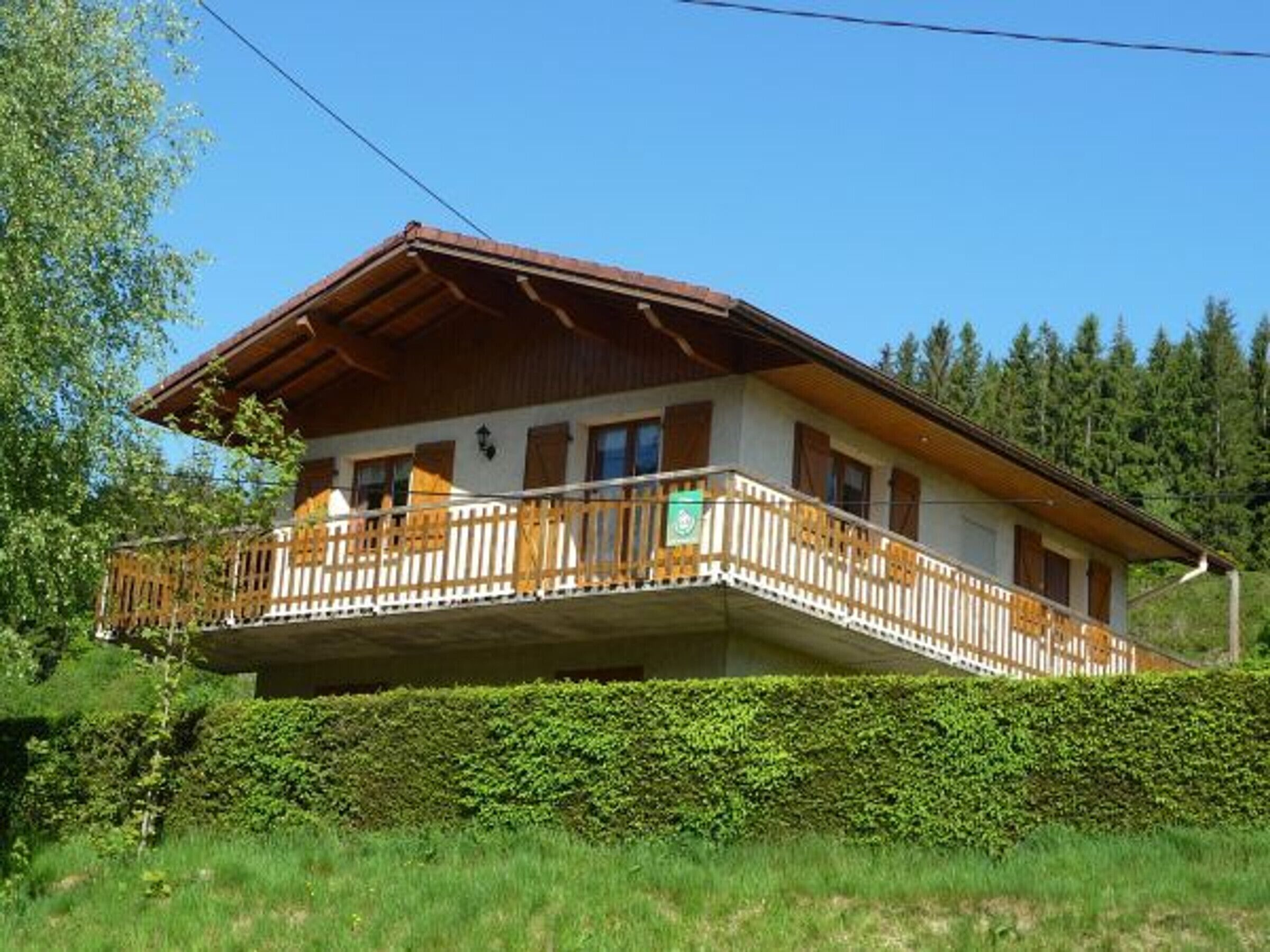 A chalet with a balcony, wooden railings, and a mountain backdrop.