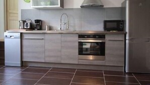 A modern kitchen with a dishwasher, oven, microwave, and a stainless steel refrigerator. - Cozy Cottage Near Epinal: Nature, City, and Equestrian Center Nearby (Chantraine)
