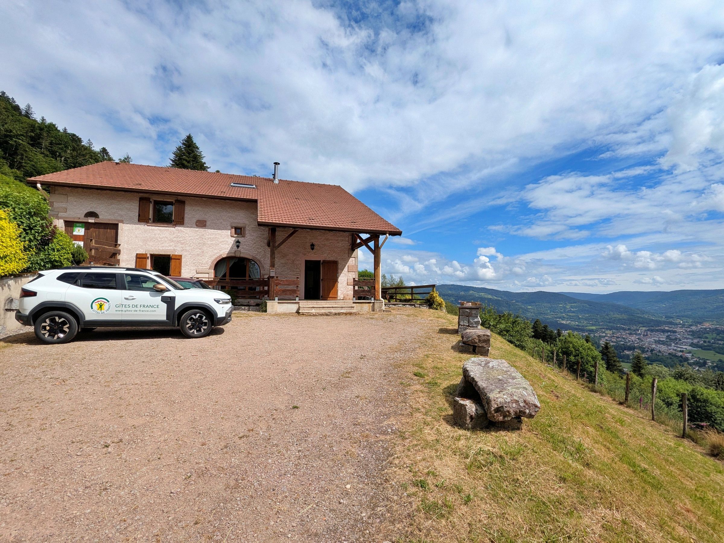 Ein Steinhaus mit einem Schotterweg, einem geparkten Auto und einem schönen Ausblick auf die Landschaft.