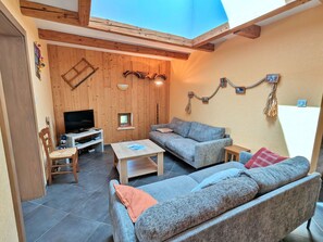Un salon chaleureux avec un plafond en bois, un canapé, une télévision et une petite table.