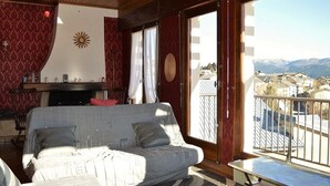 Una sala de estar acogedora con un sofá, una mesita y vistas a un pueblo desde un balcón.