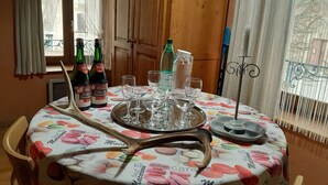 A dining table with a floral tablecloth, wine glasses, bottles, and a decorative antler centerpiece.
