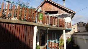 A two-story wooden house with a balcony, a chimney, and a sign indicating it is a guesthouse.