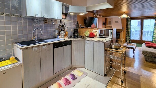 A modern kitchen with a central island, stainless steel appliances, and a view of the city through large windows.